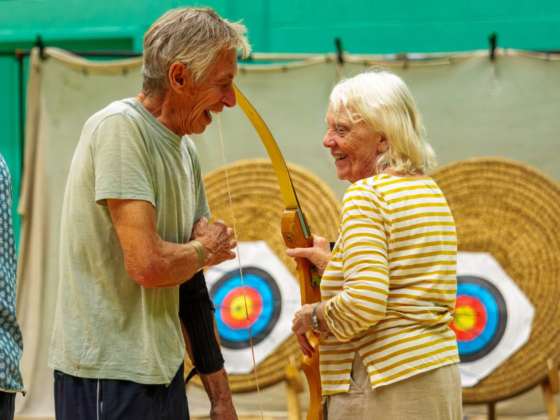 Older adults smiling whilst enjoying archery