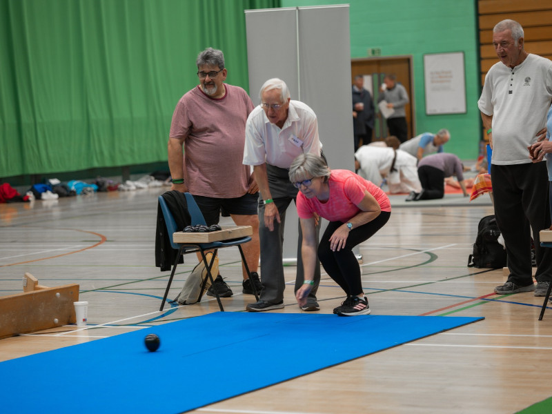 Older adults playing indoor carpet bowls